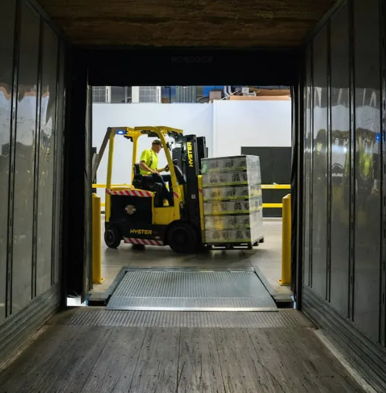 Forklift operator loading pallet into truck at warehouse — efficient delivery and logistics handling