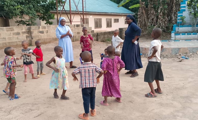 Catholic nuns play outdoor games with local children at an African community center.