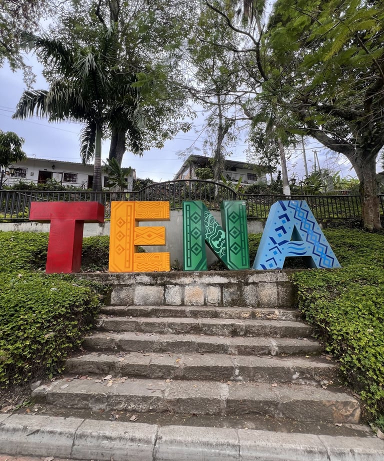 Colorido letrero de la ciudad de Tena con patrones indígenas sobre escaleras de piedra en la región 