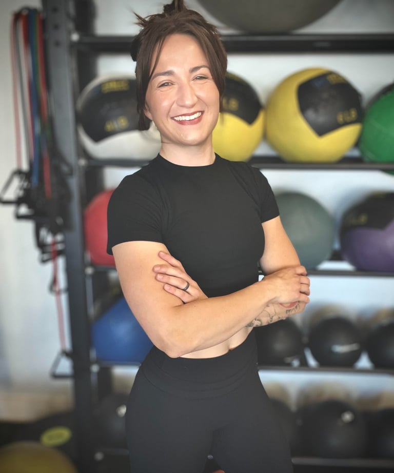 Female Personal Trainer standing in front of a medicine ball rack
