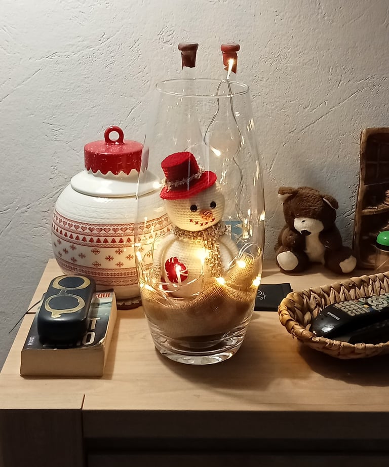 Bonhomme de neige avec un chapeau rouge et une écharpe dans un grand vase lumineux 