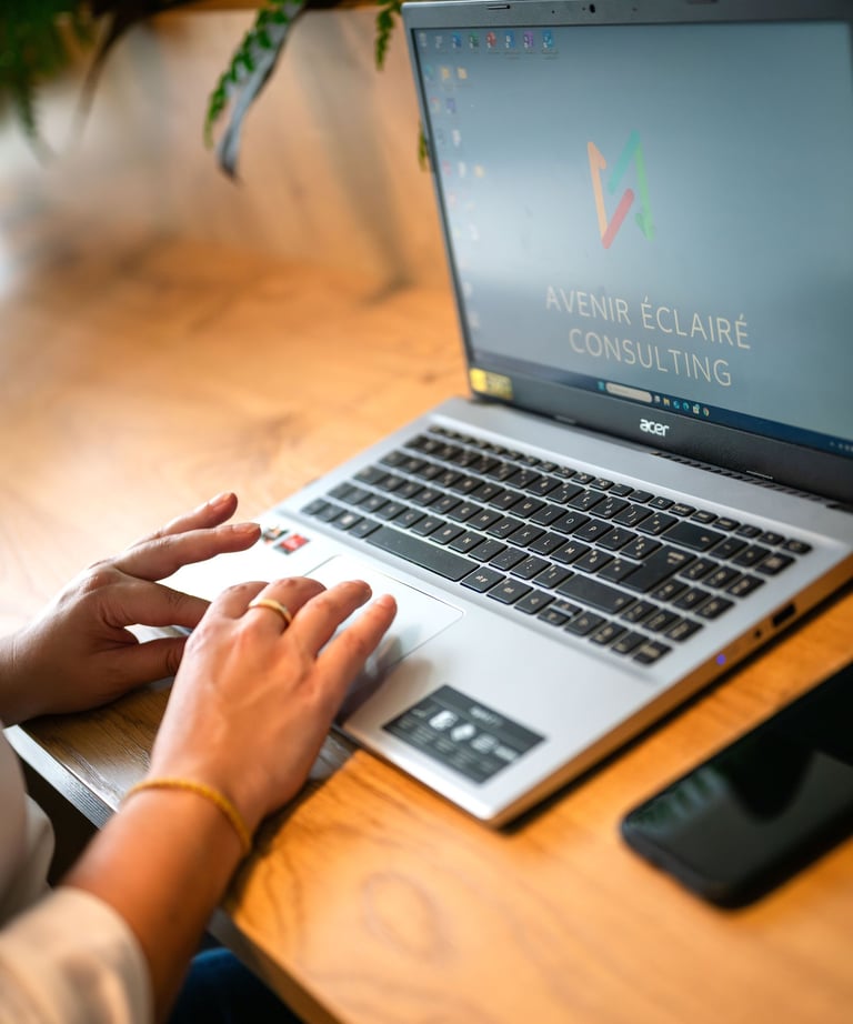 Mains d'un consultant sur un ordinateur portable avec le logo Avenir Éclairé Consulting 