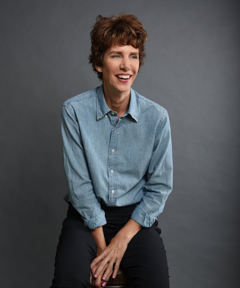 professional studio photo of author Dawn Davies sitting on a bench and smiling