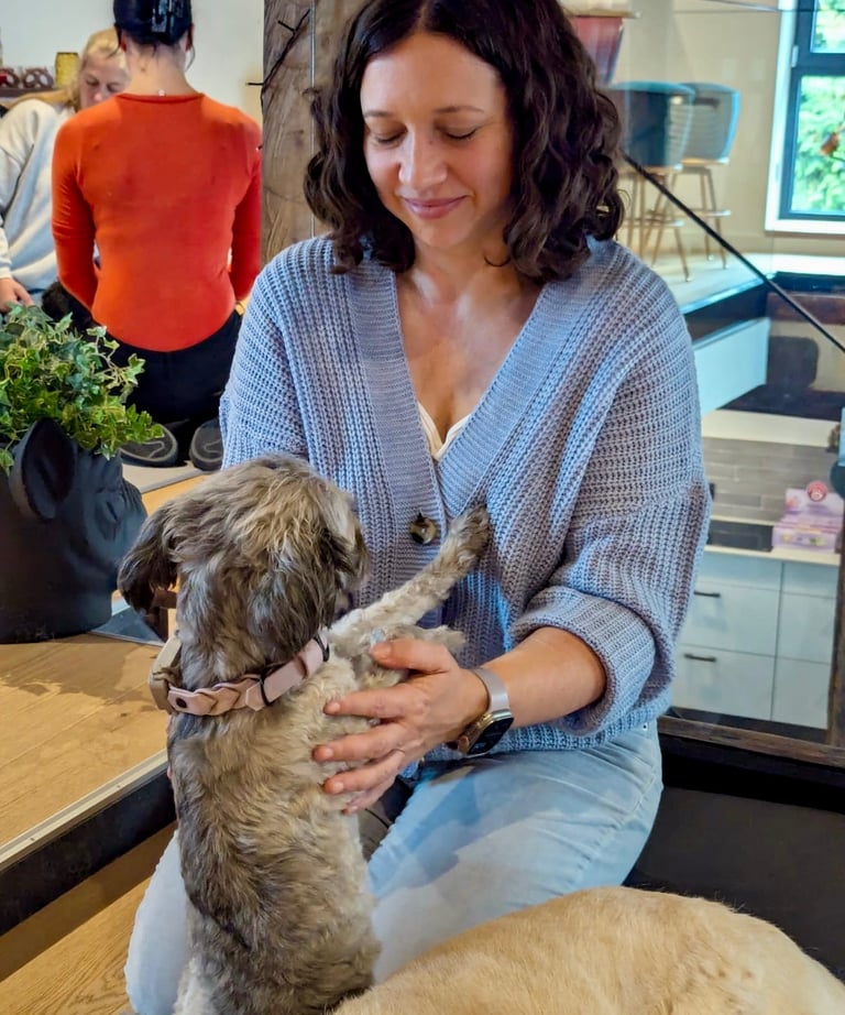 Svenja sitzt im Fersensitz, währen Pudel Paula ihr die Vorderpfoten auf die Brust legt.