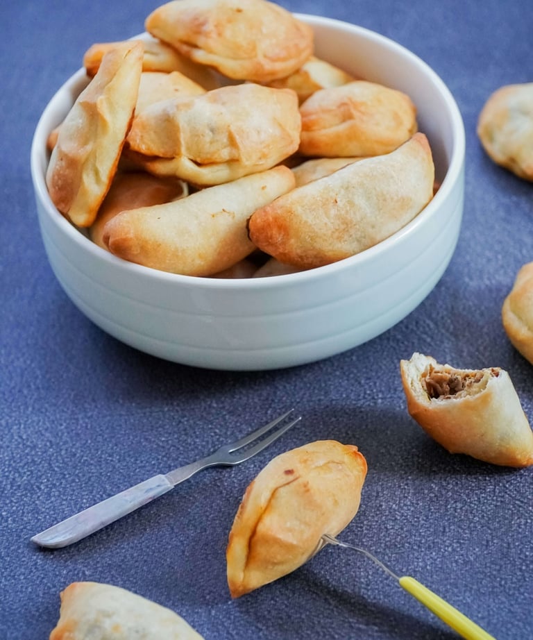 Zdjela puna punjenih piroga servirana na plavom stolnjaku.