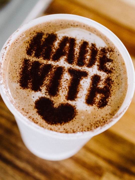 Latte art heart with “made with love” message on a coffee cup