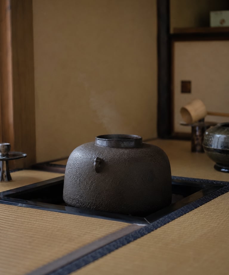 Steaming traditional Japanese cast iron tea kettle sitting in a sunken hearth on a tatami mat.