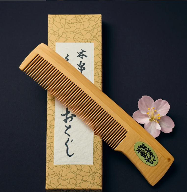 Traditioneller japanischer Holzkamm aus Tsuge, fein gearbeitet und neben Kalligrafiepapier sowie ein