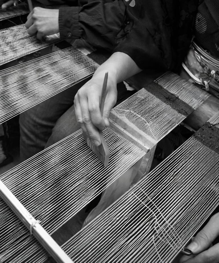 Close-up of a weaver using a traditional wooden comb tool on a handloom for intricate textile weaving.
