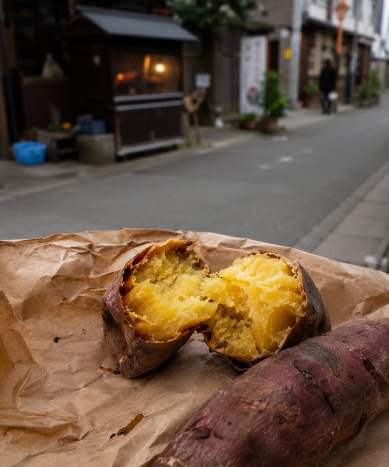 Roasted Japanese sweet potato split open on brown paper with a blurred Tokyo street background.