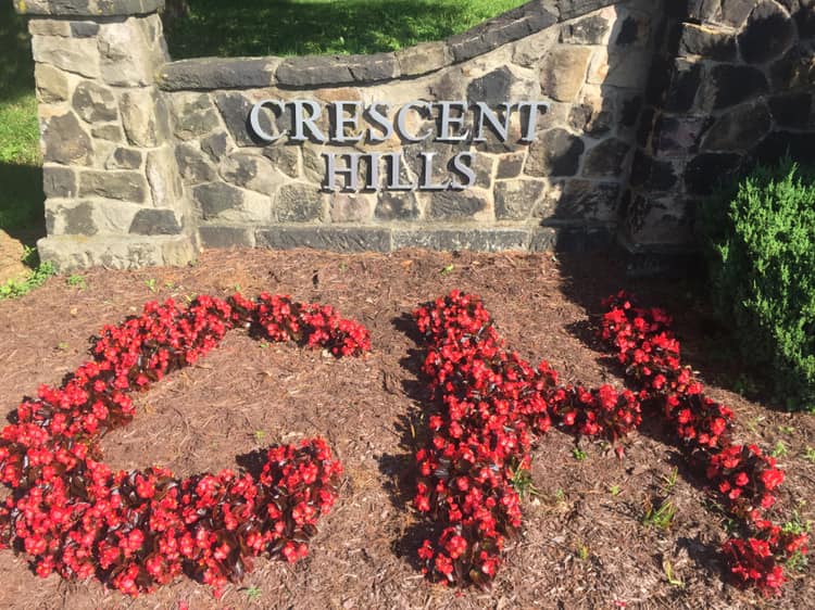 Crescent Hills stonework sign and red flowers spelling C H
