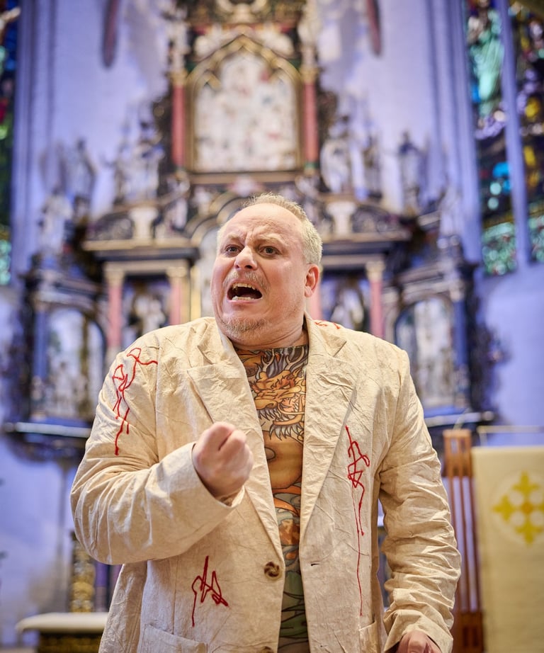 Ein Schauspieler ruft sehr emotional. Hinter ihm ein Kirchenaltar.