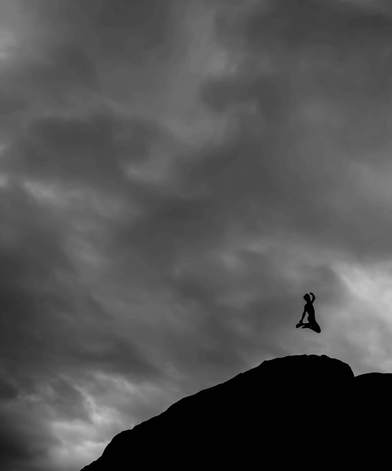 The shadow of a person jumping joyfully on a mountaintop, on a gray and cloudy day