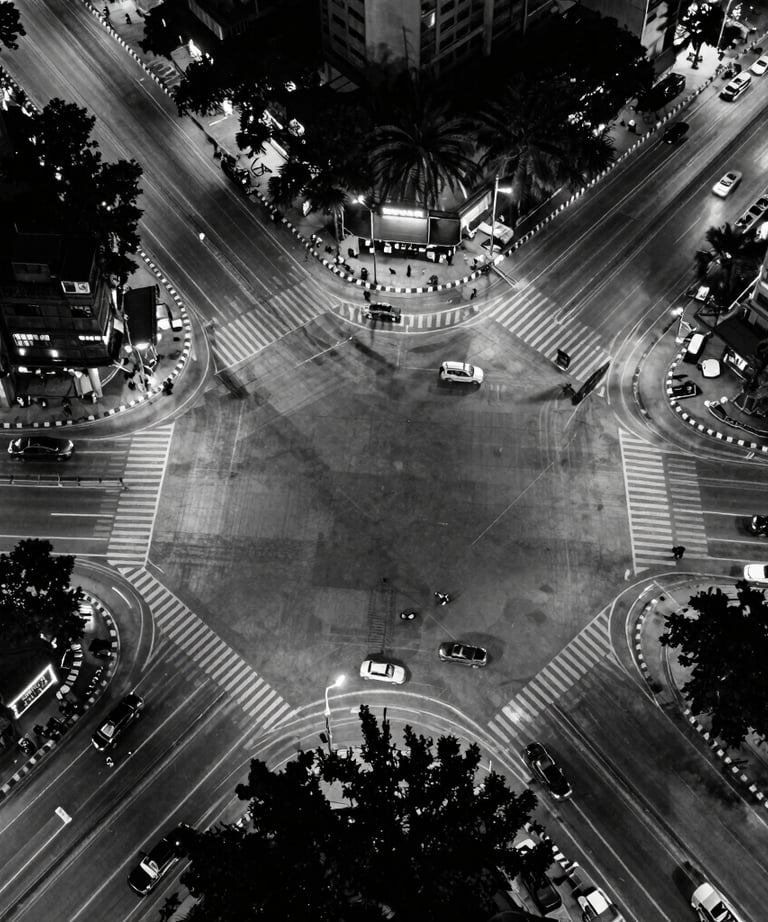 A bird's eye view of a modern Pune intersection at night, captured in high-contrast black and white, representing the urban energy of our base.
