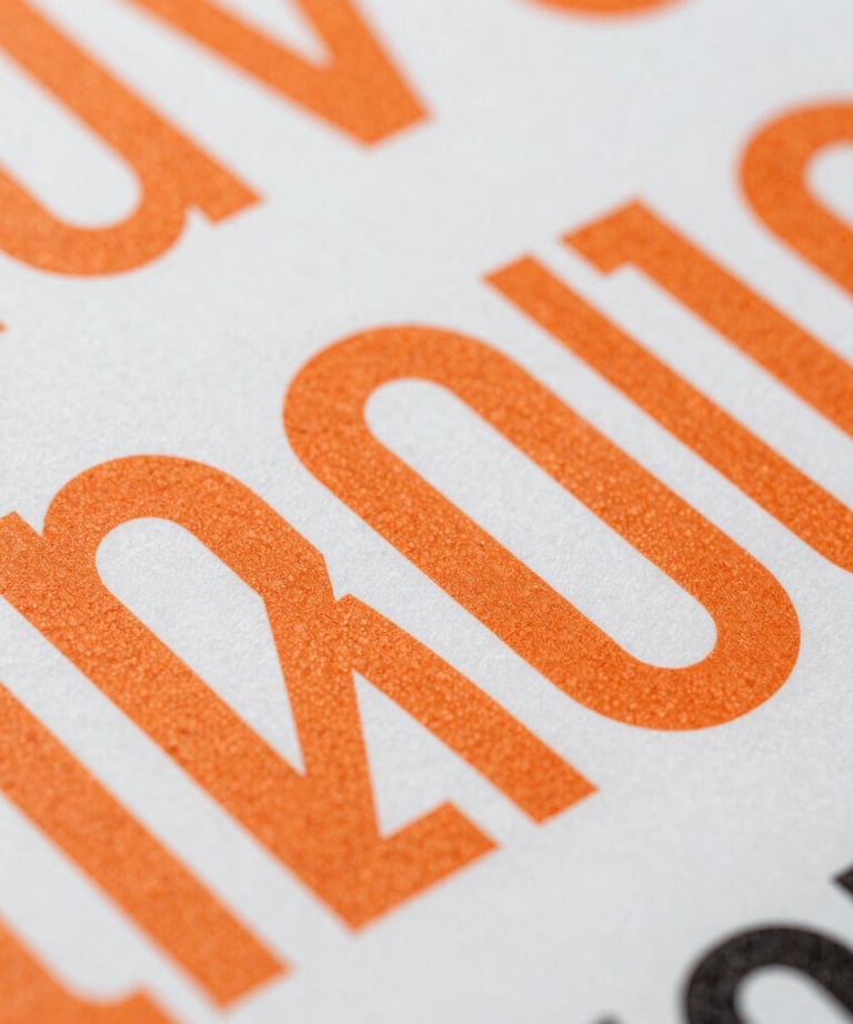 Abstract close-up of high-quality printed materials with bold typography and orange ink, focusing on texture and professional finish.