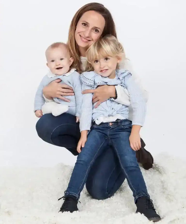 a woman sitting on a rug with two children