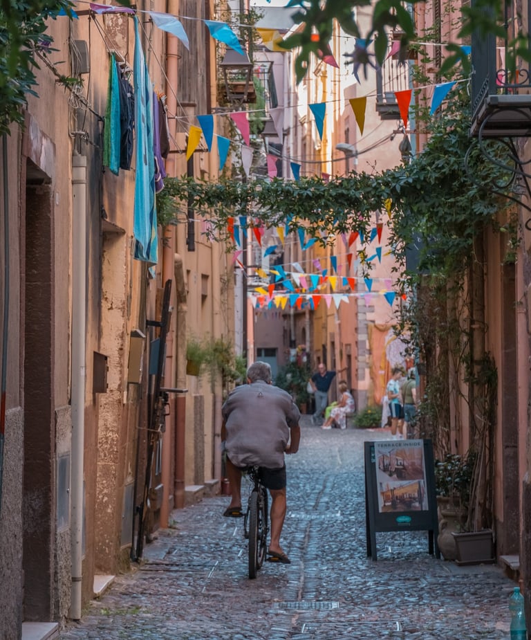 Man riding a bicycle in a cobblestone street in Bosa, Sardinia