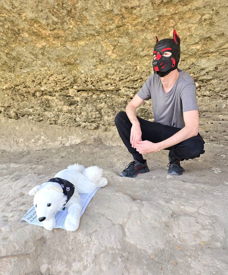 A man in a pup mask and his stuffed plushie dog.