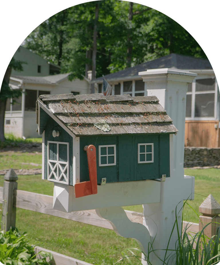 green and white handmade mailbox on a white post