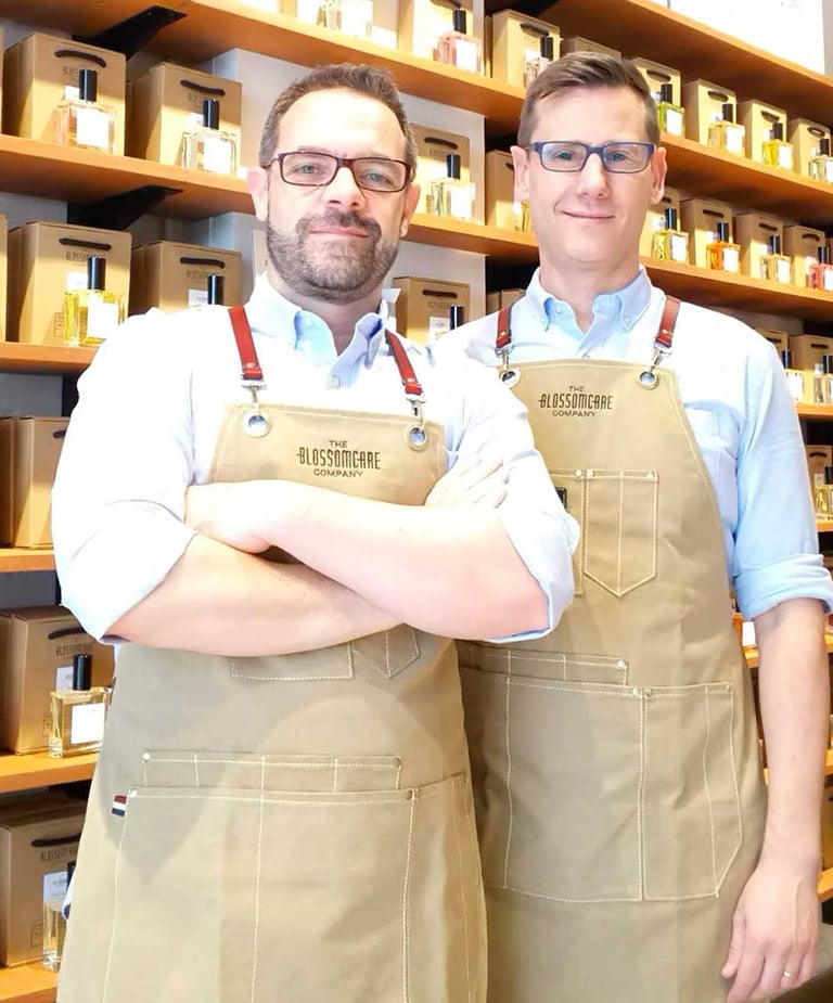 Kvepalų kūrėjai iš Valensijos, o už jų – lentyna pilna įvairių nišinių, jų kurtų kvepalų.