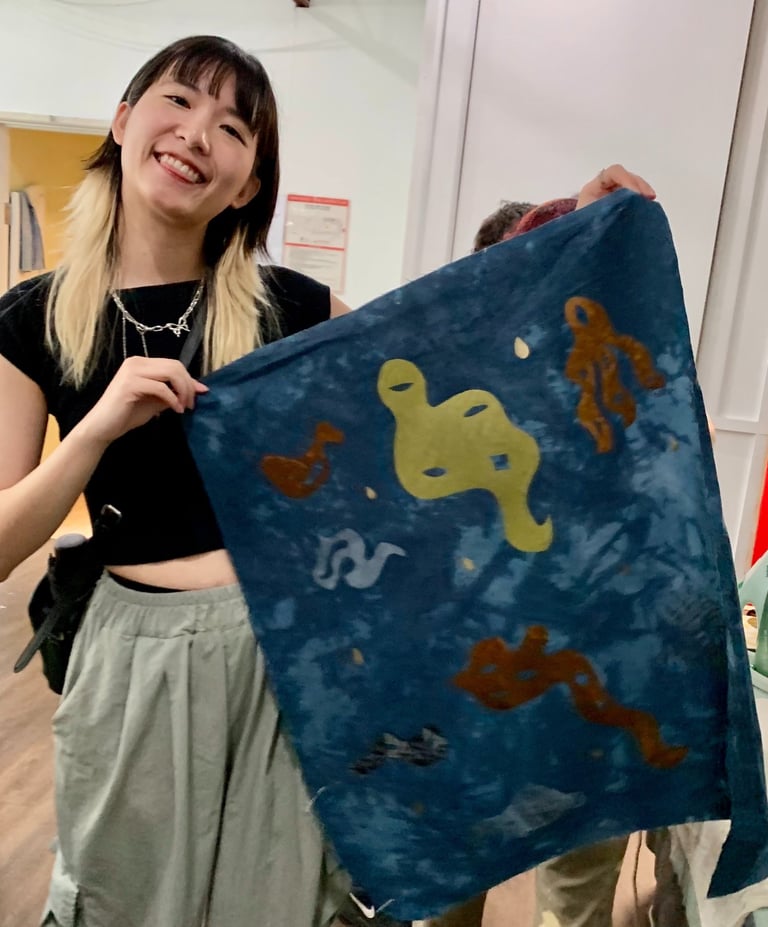 A person with blonde and black hair and light skin holds a banner smiling.