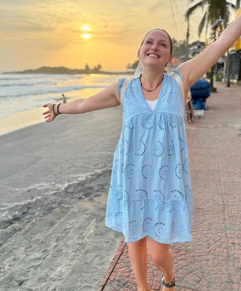 Alena Booth smiling with her hands wide open happy to be in India and seeing the sunset