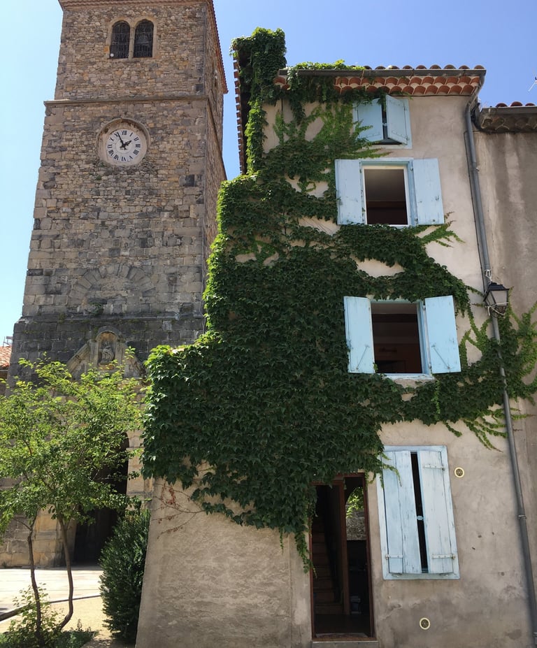 Tour d’horloge historique en pierre à côté d’une maison de village à Quillan, 