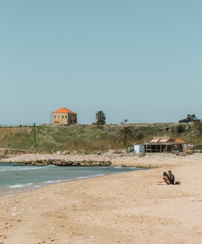 A couple sits on a sandy Mediterranean beach in Jbeil, Lebanon by Lebanese photographer Emma Jowdy