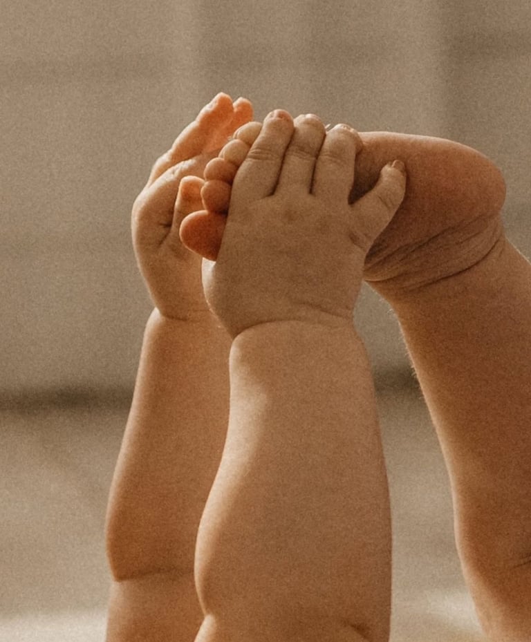 un bebe se tenant les pieds avec ses mains 