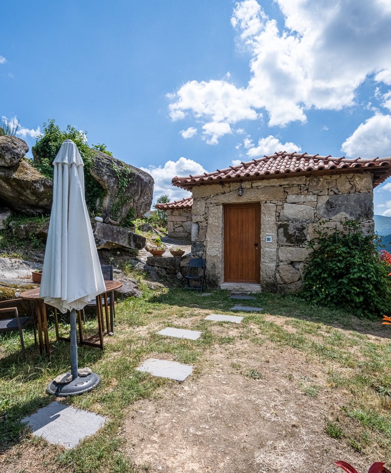 a small stone building with a white umbrella