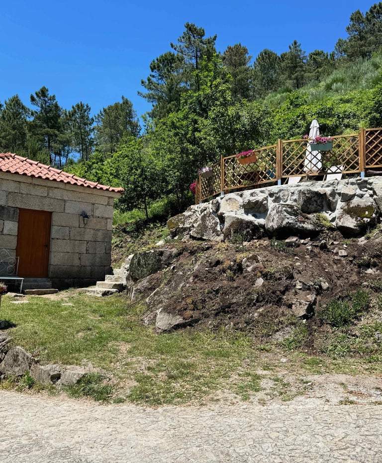 a small stone building with a stone wall and a small stone building