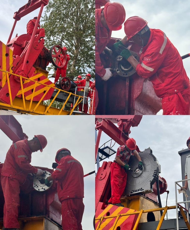 Oil field workers in red uniforms and hard hats perform maintenance on a pumping unit machine.