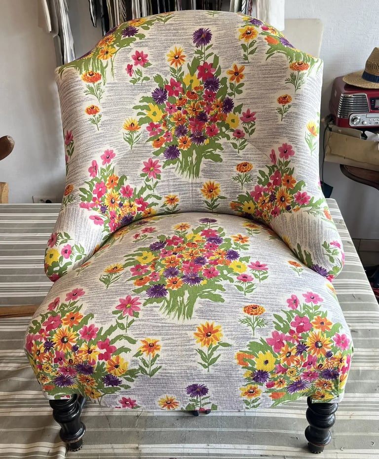 Chauffeuse Napoléon III recouverte d'un tissu à motif floral sur fond gris