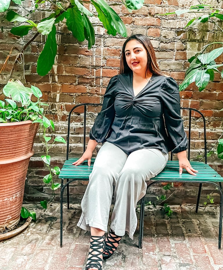 patricia sitting on a bench in a garden surrounded by plants