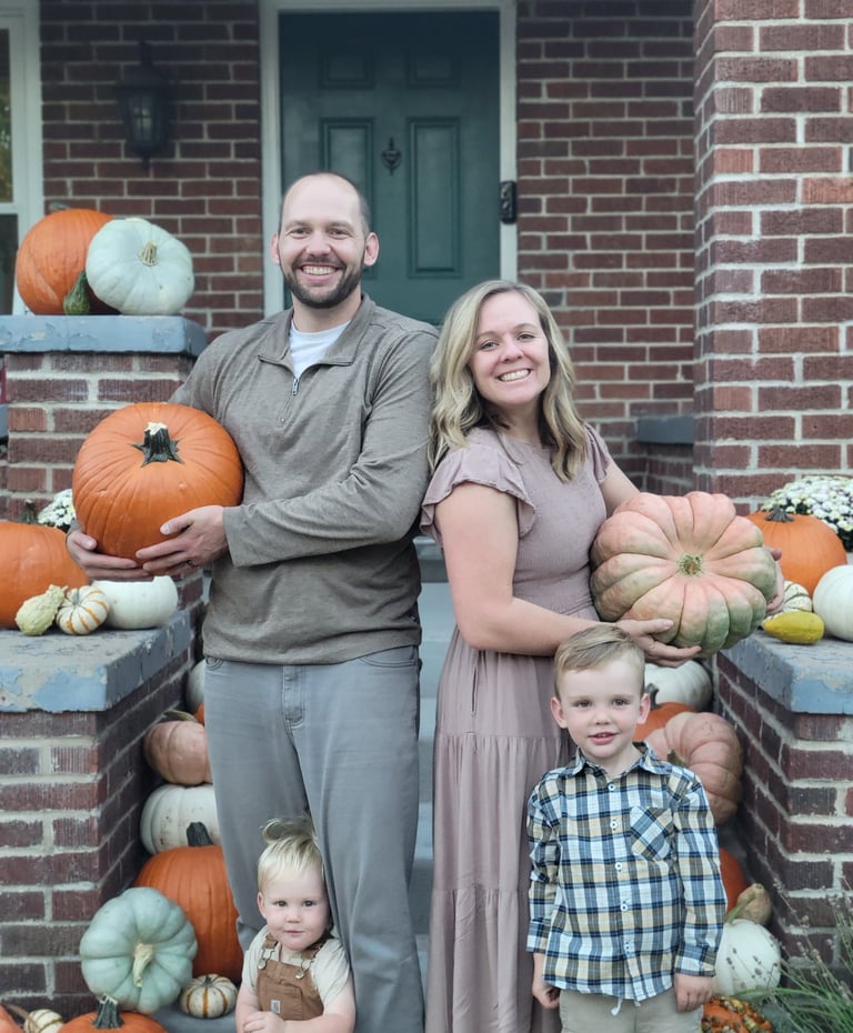 a family posing for a family photo surrounded by pumpkins in front of a house