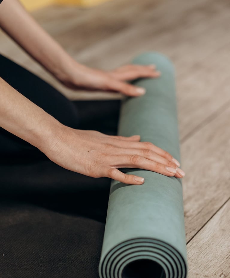 Hände, die eine Yogamatte aufrollen