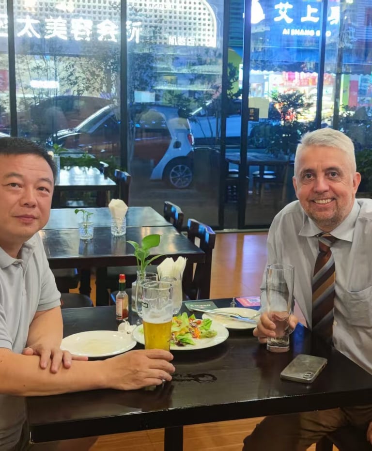 Two business colleagues enjoying dinner and beer at a city restaurant table with window views.
