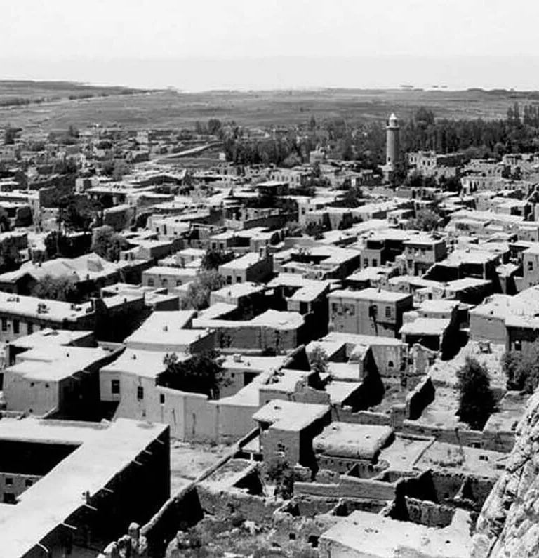 Historic aerial view of an ancient Middle Eastern city featuring traditional stone architecture and a minaret.