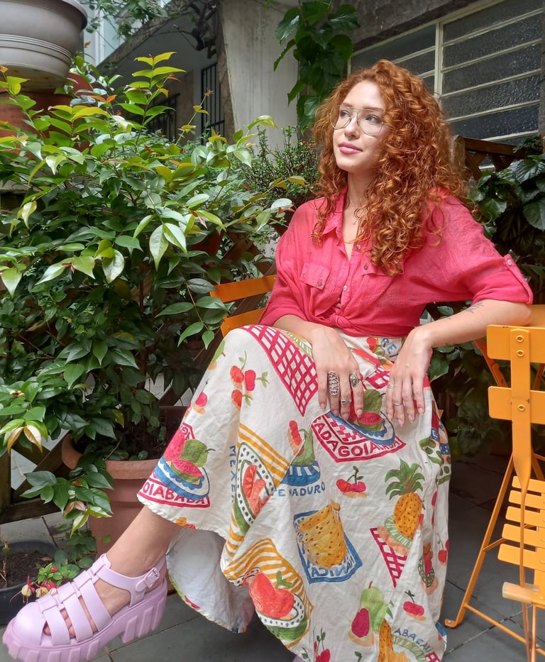 Sabrina Tibursky sentada de pernas cruzadas em frente a plantas