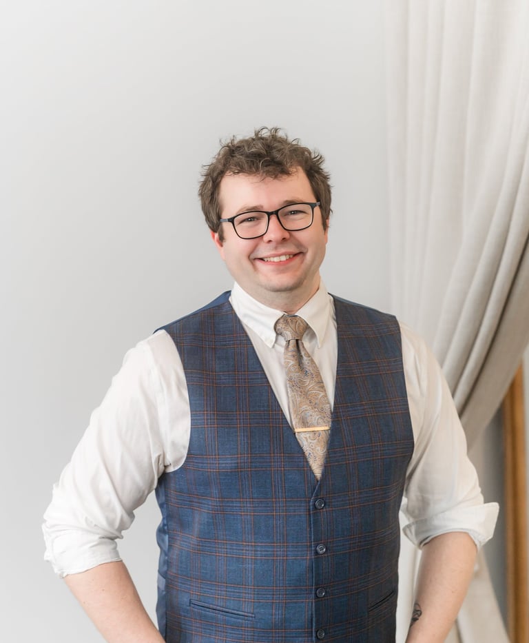 Picture of Rocco Catrone smiling at camera with glasses, a gold tie, and vest.