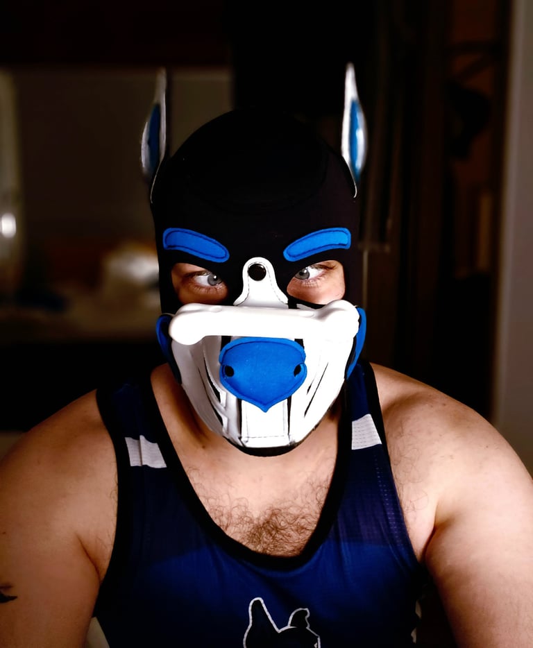 Man in a pup mask with a toy balancing on his nose.