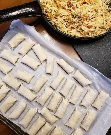 uncooked Thai spring rolls ready for freezing on parchment paper on a cookie sheet