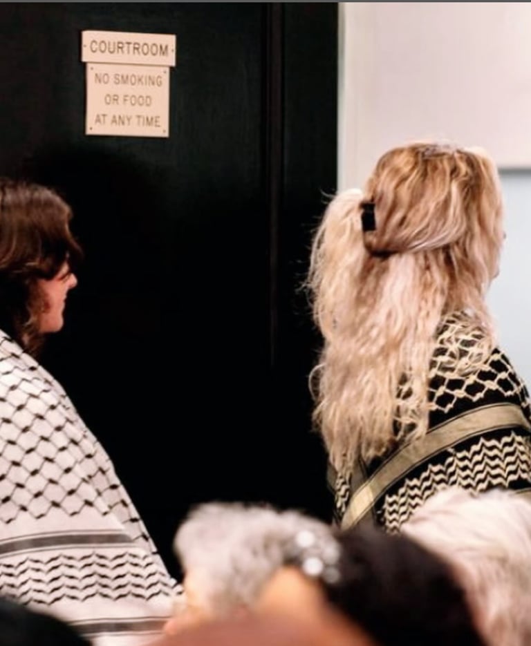 two women wearing keffiyehs walk out of a courtroom in Chapel Hill, NC