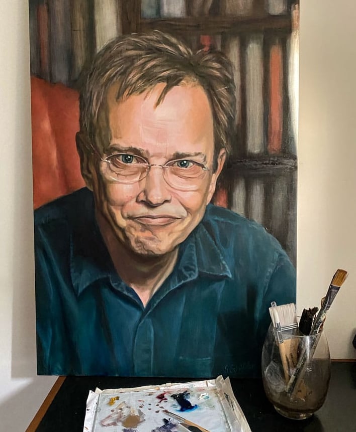 Oil painting and brushes of man with glasses by bookshelf.