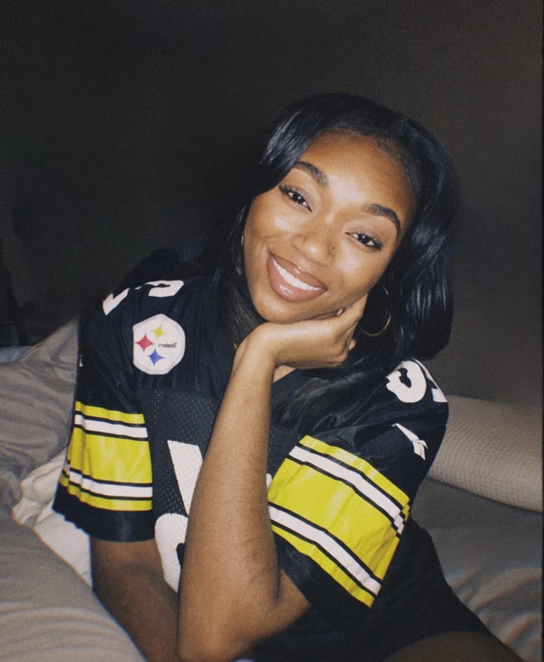 a woman in a jersey shirt is smiling and holding her hand on her chin