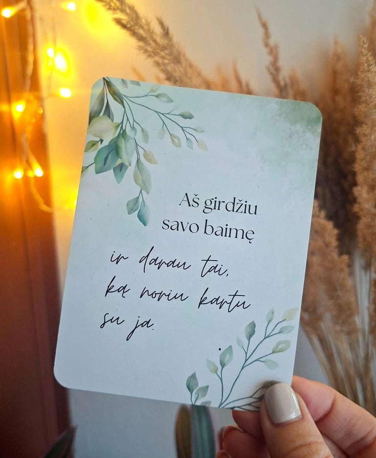 Afirmacijos kortelė su tekstu "Aš girdžiu savo baimę" laikoma rankoje