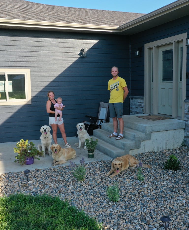 A family with their 4 dogs in front of a house