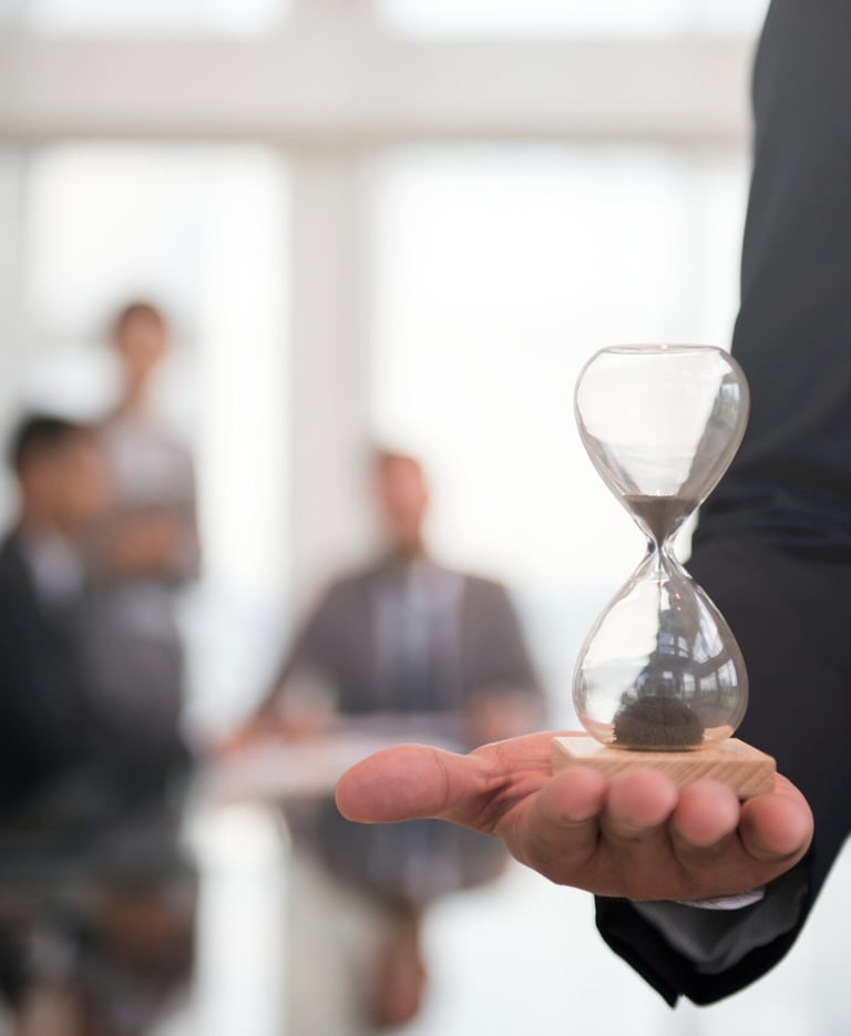 Professional businessman holding a glass hourglass to symbolize corporate time management and deadlines.