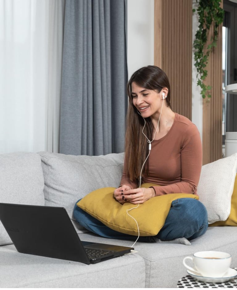 a woman sitting on a couch with a laptop and headphones