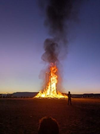 a person standing in front of a large bonfire at Afrikaburn